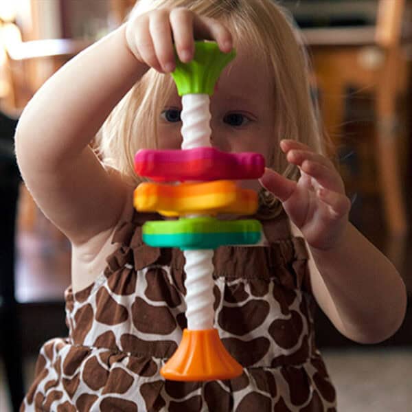 Child playing with colorful stacking toy indoors.