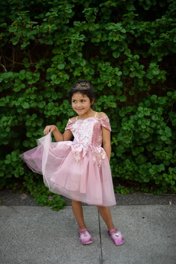 Child in pink dress posing outdoors happily.