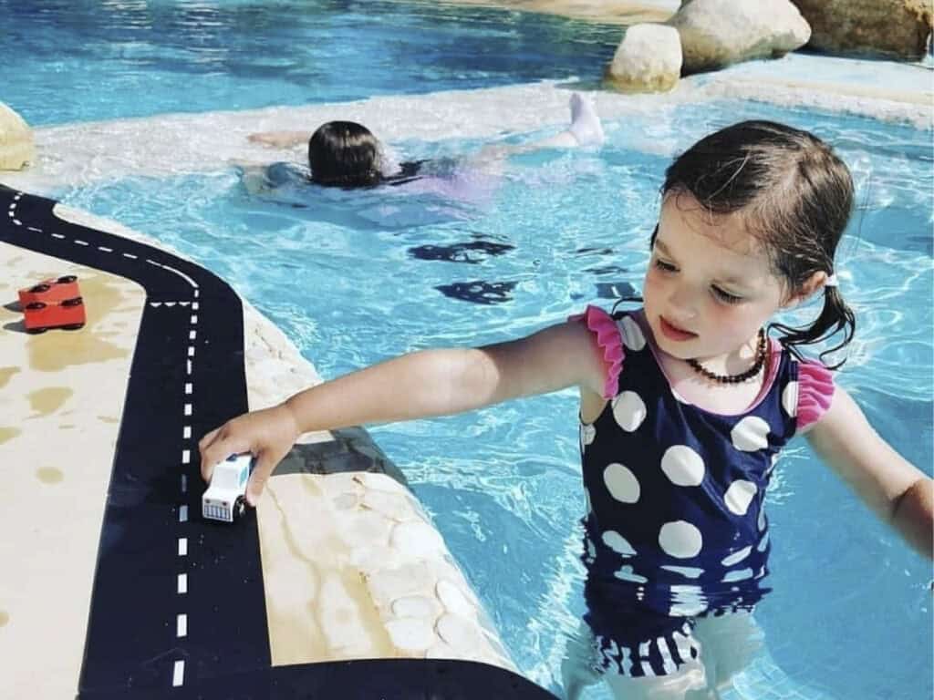 Child playing near pool with toy car