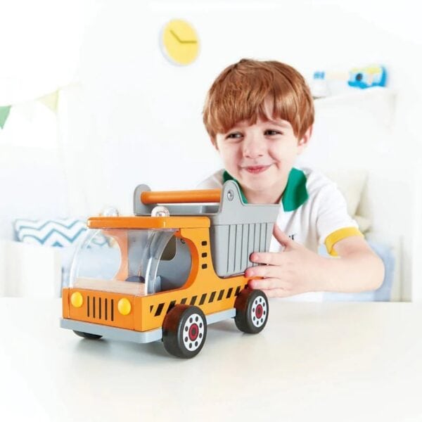 Child playing with toy dump truck indoors.