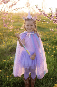 Child in unicorn costume, field of flowers.
