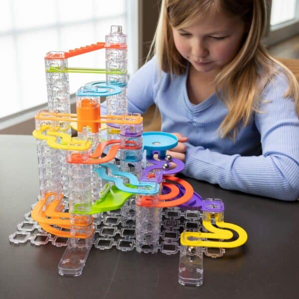 Child playing with colorful marble run toy set.