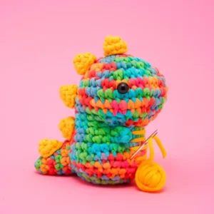 Colorful crocheted dinosaur toy with knitting needle.