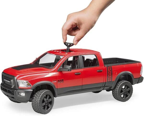 Hand holding red toy truck steering wheel