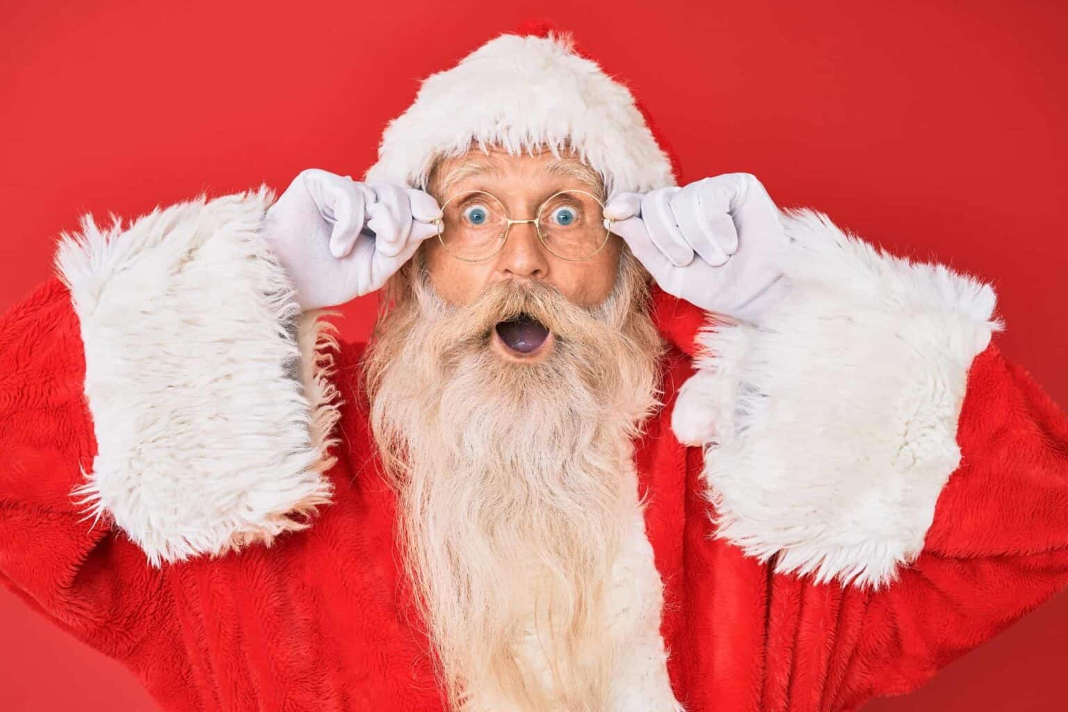 Surprised Santa Claus with glasses, red background.