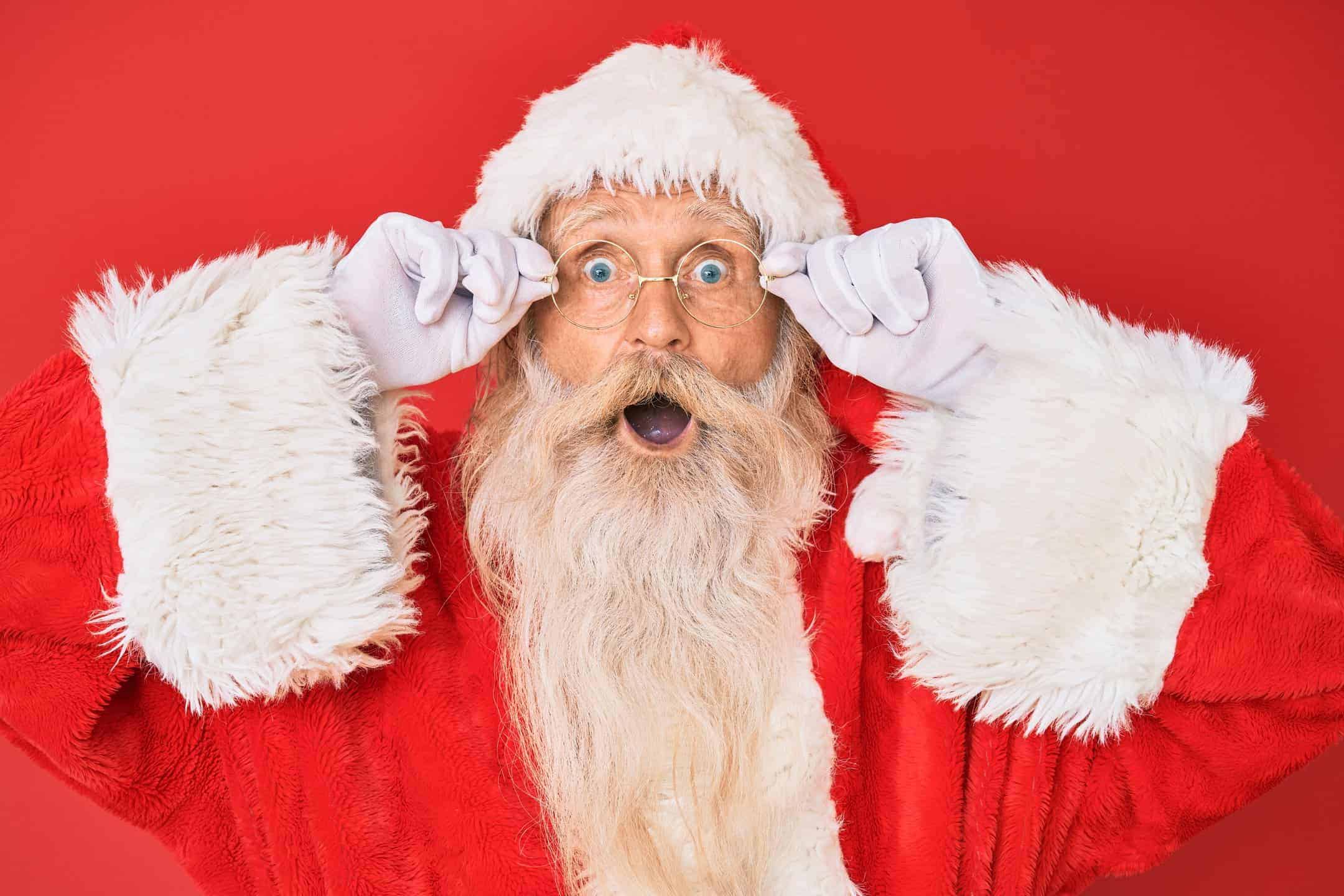 Surprised Santa Claus with glasses, red background.