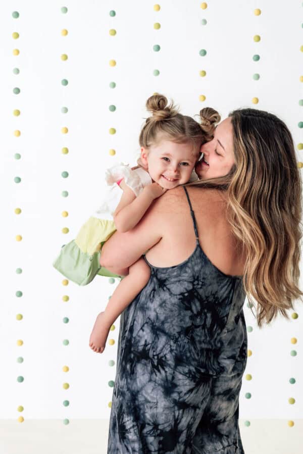 Mother holding smiling child against dotted backdrop.
