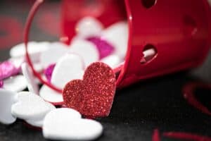 Glitter hearts spill from red bucket.