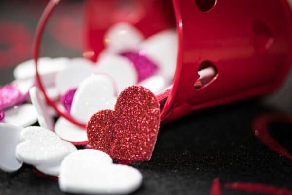 Glitter hearts spill from red bucket.