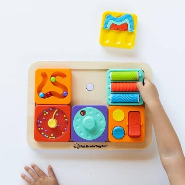 Child playing with colorful sensory toy board.