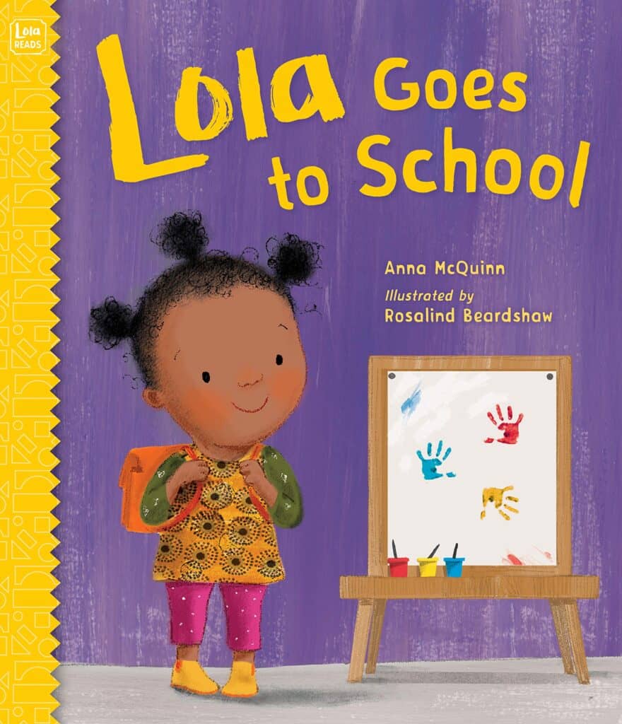 Child with backpack near colorful handprints easel.