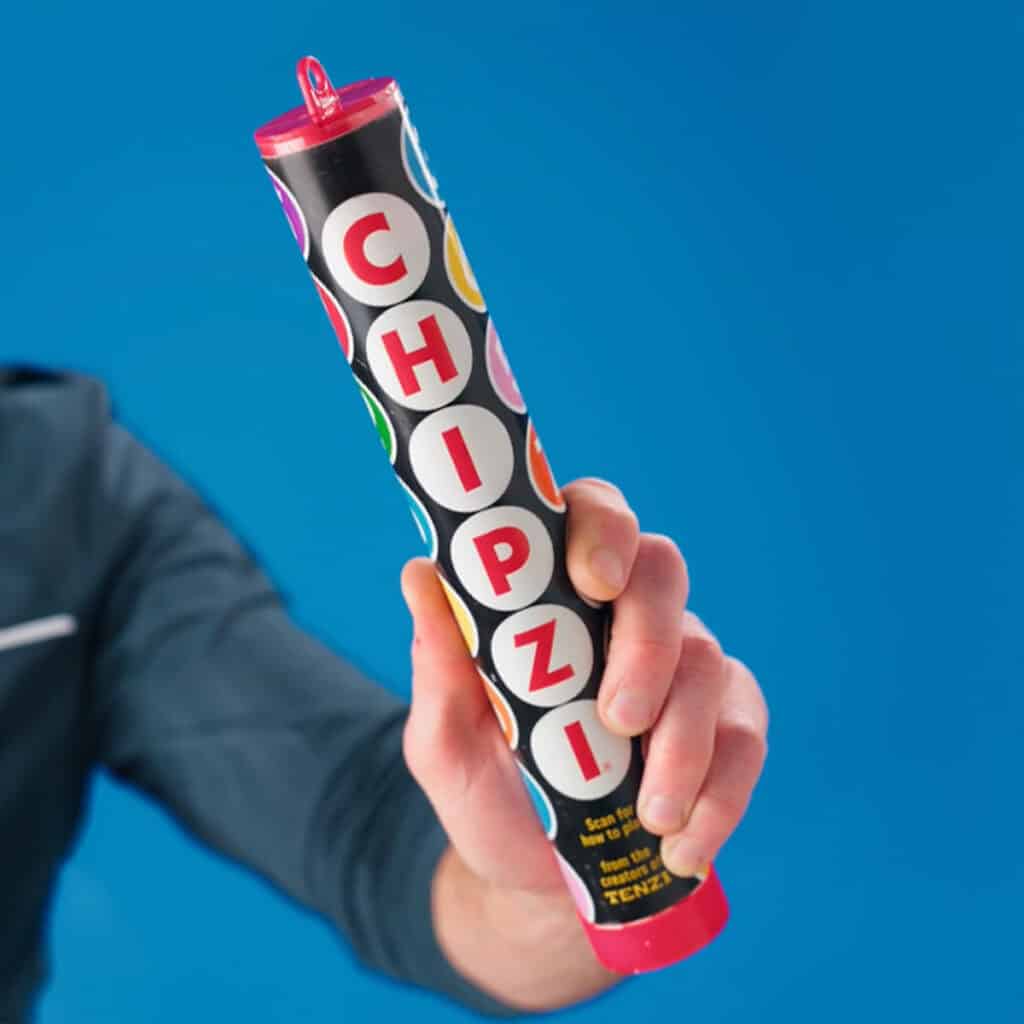 Hand holding colorful Chipzi stick against blue background.
