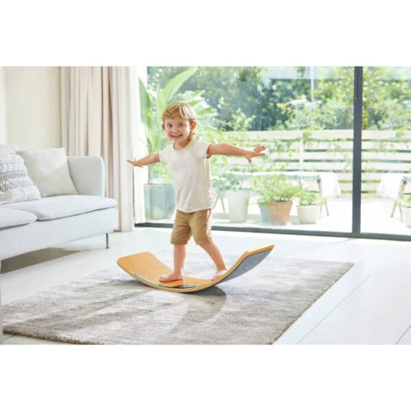 Child balancing on a wooden board indoors
