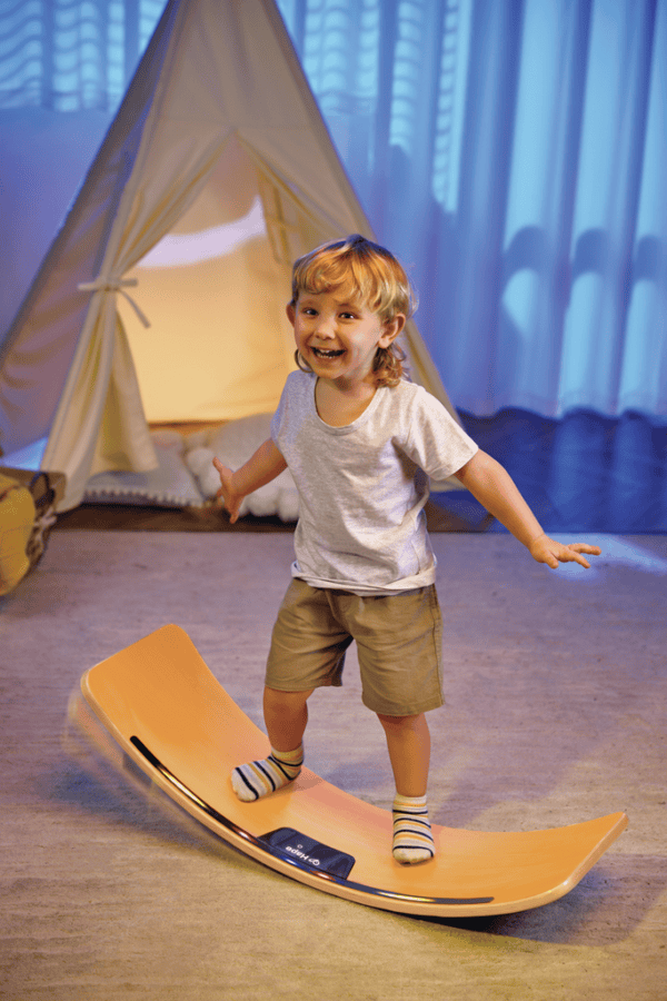 Child balancing on wooden board indoors.