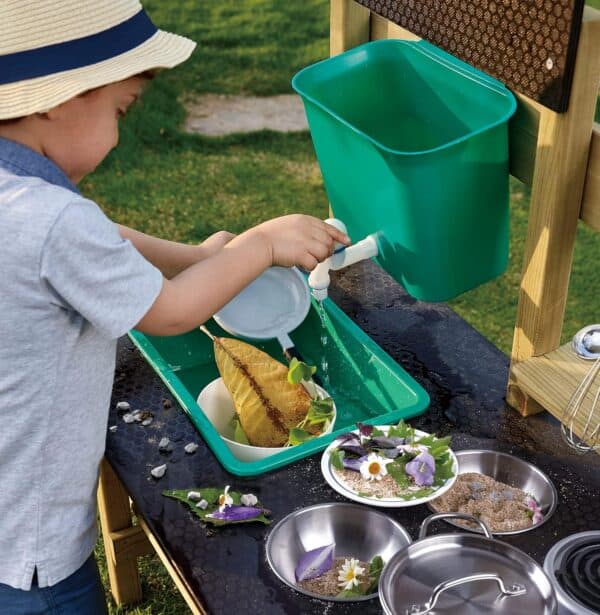 Child playing in outdoor mud kitchen with water.