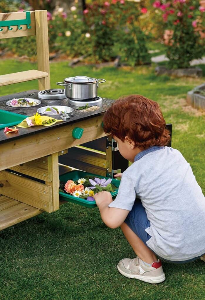 Child plays with outdoor mud kitchen flowers.