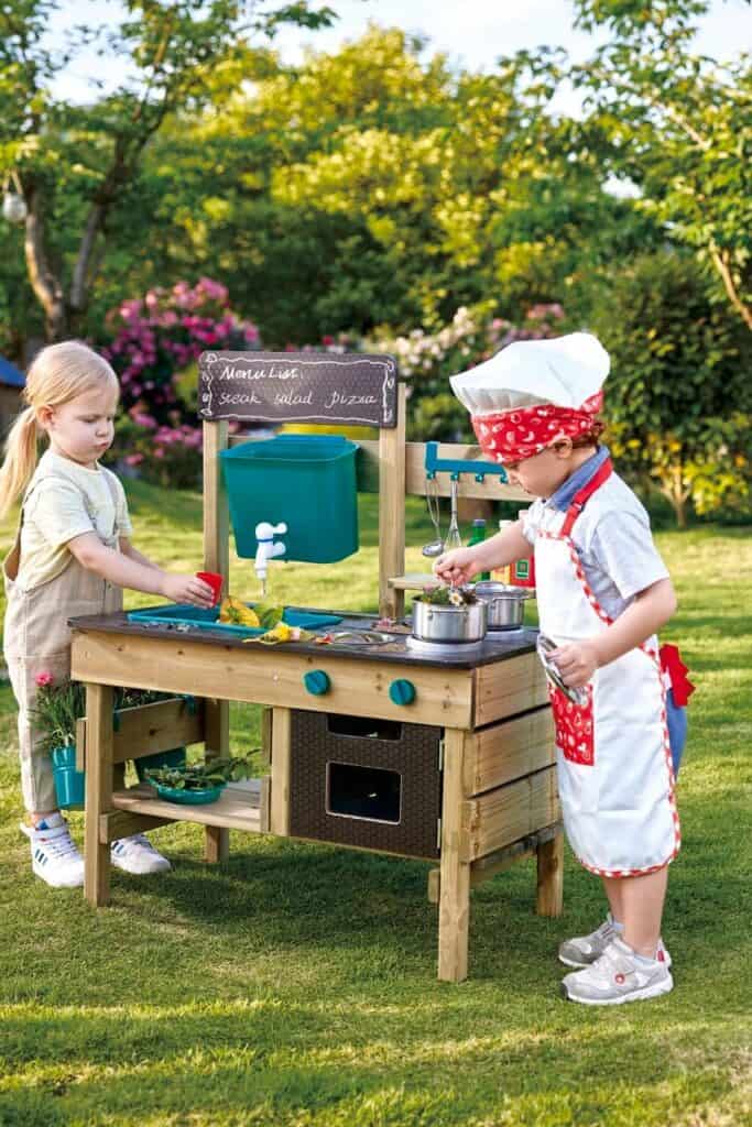 Children playing with outdoor wooden kitchen set.