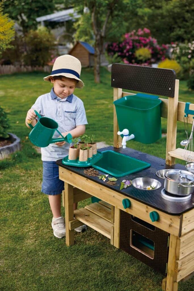 Child watering garden plants in play kitchen