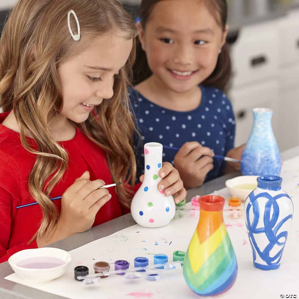 Kids painting colorful ceramic vases together.