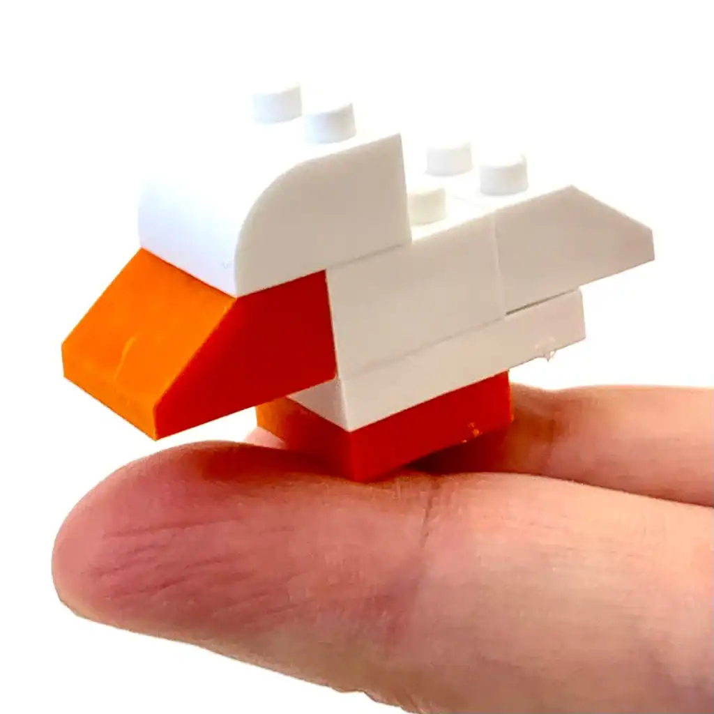 Lego duck model resting on a fingertip.