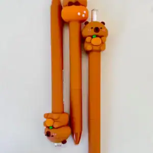 Three orange pens with cute bear designs.