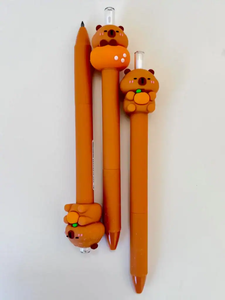 Three orange pens with cute bear designs.