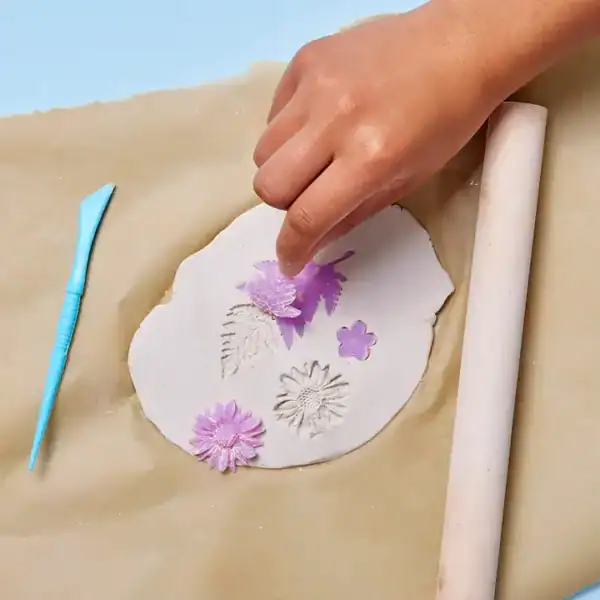Hand crafting clay with floral impressions