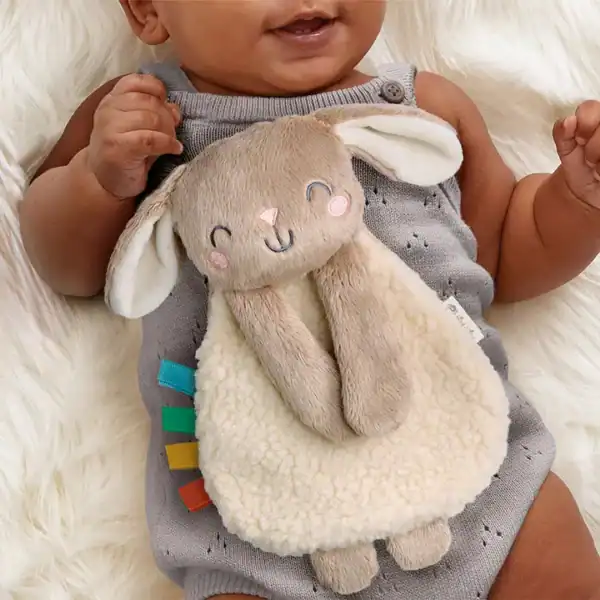 Baby with plush bunny toy on tummy.