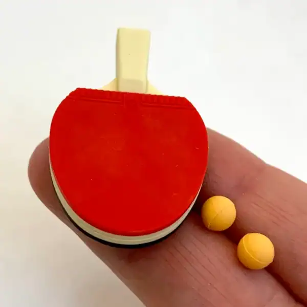 Miniature table tennis paddle and balls on fingertip.