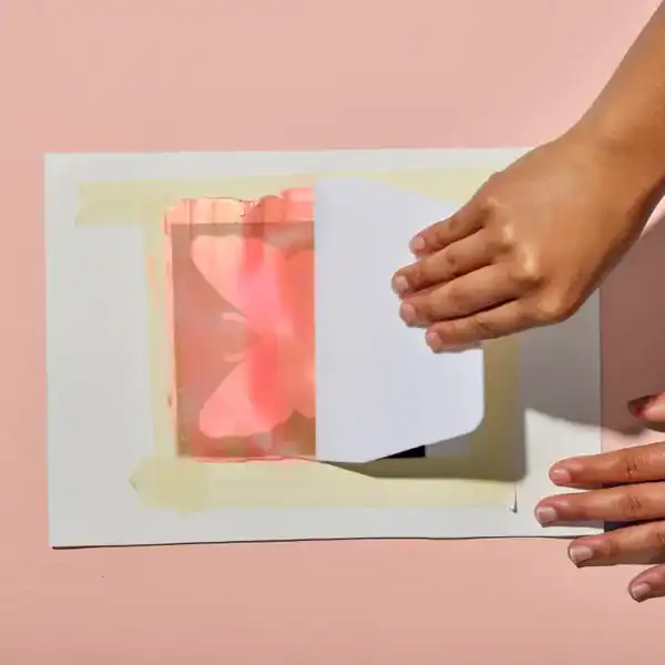 Hand removing paper from butterfly print stencil.