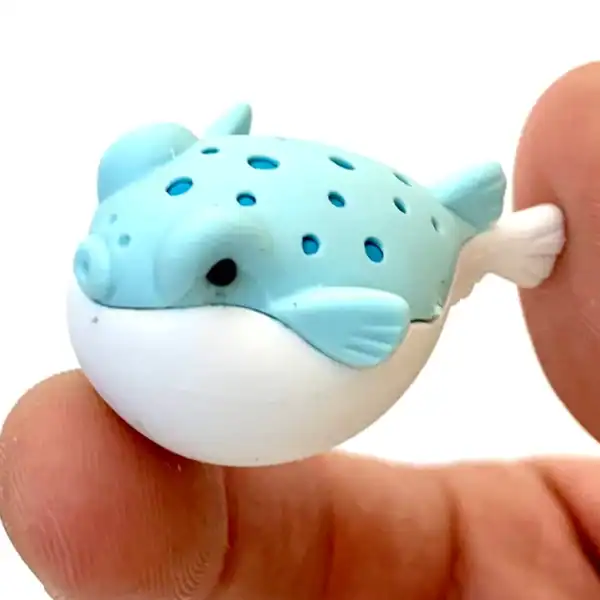 Blue toy pufferfish held between fingers.