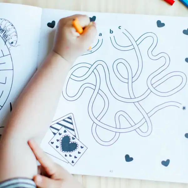 Child coloring a maze with pencil