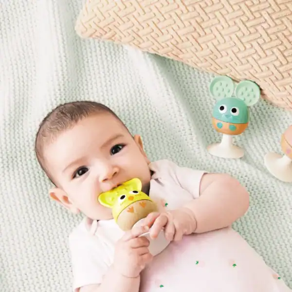 Baby playing with colorful toy on blanket.
