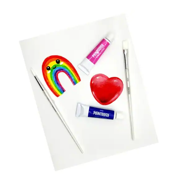 Colorful rainbow, heart, paint tubes, and brushes on paper.