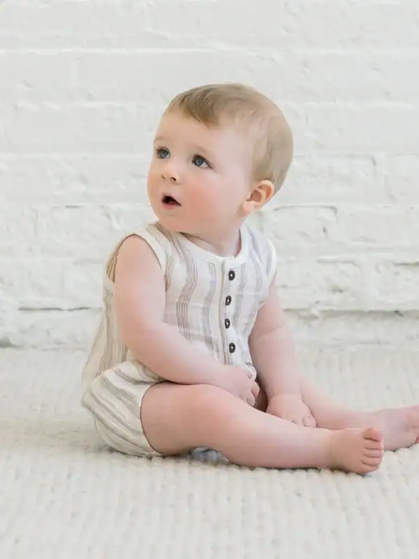 Baby sitting on soft carpet indoors.