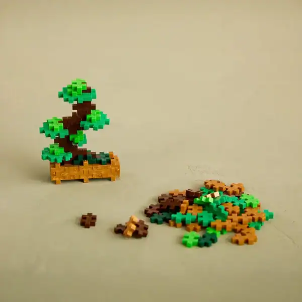 Mini building block bonsai tree with loose pieces nearby.