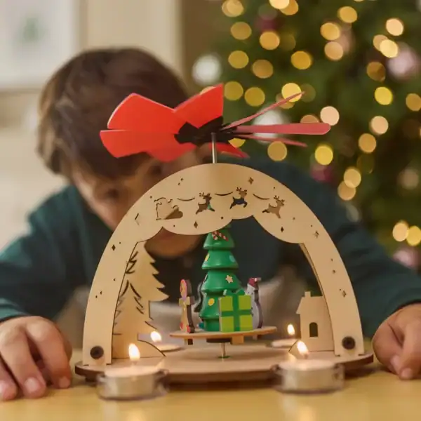 Child admiring holiday centerpiece with candles and tree.