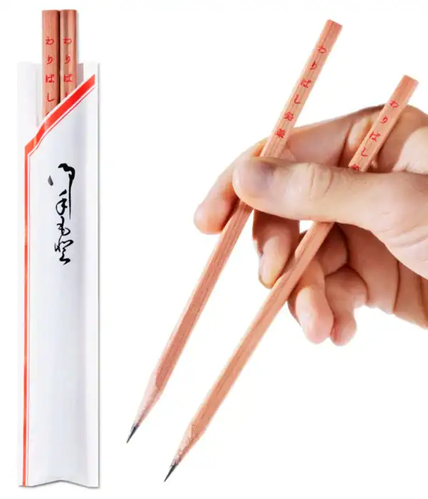 Hand holding pencil-shaped chopsticks, packaging beside.