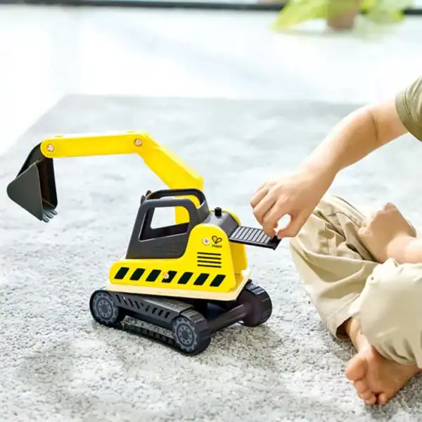 Child playing with toy excavator on carpet.