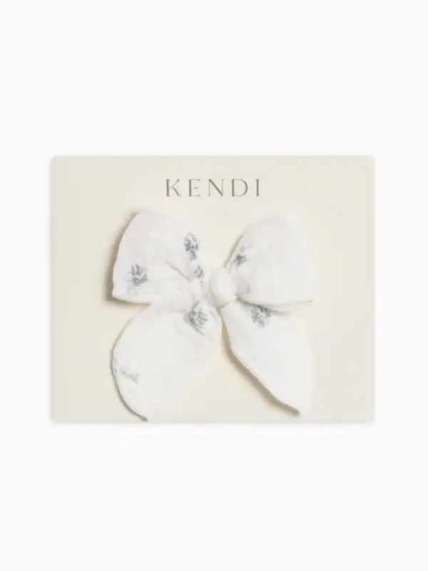 White bow with blue embroidery on card.