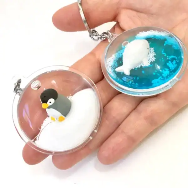 Penguin and seal keychains in a hand.