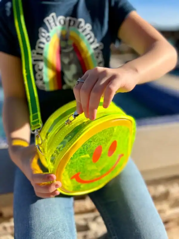 Person holding neon smiley face bag.