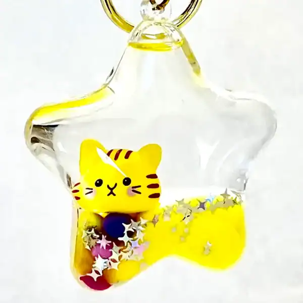 Star-shaped charm with yellow cat and glitter.