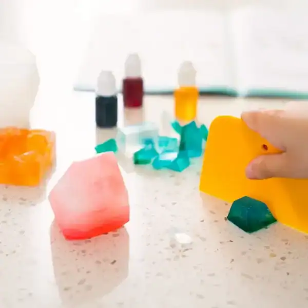 Colorful gems and bottles on a table, hand touching.