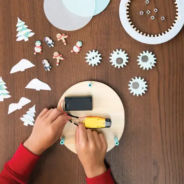 Child assembling a mechanical craft with holiday decorations.