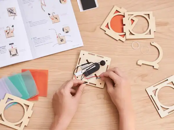 Hands assembling wooden electronic project kit