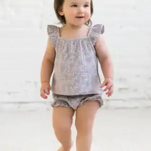 Smiling toddler in grey outfit with a bow.