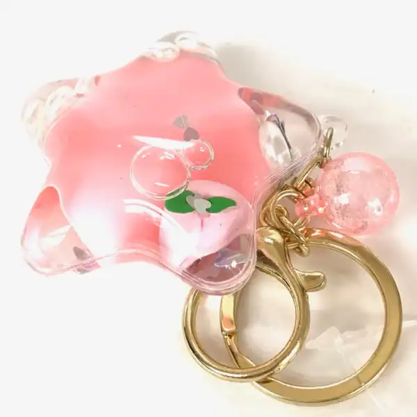 Pink star-shaped keychain with bubbles and gold ring.