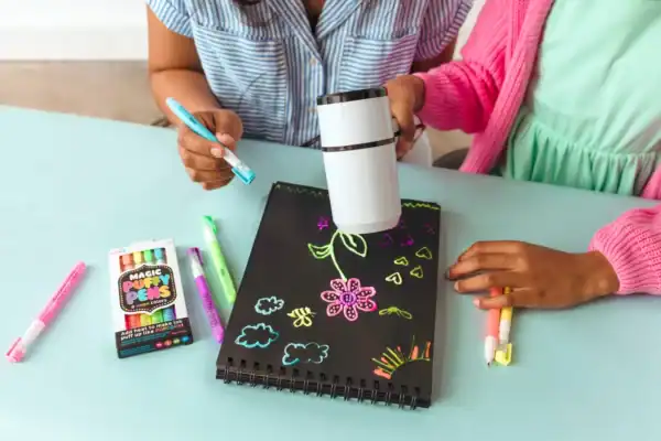 Children using puffy pens to create glowing art.