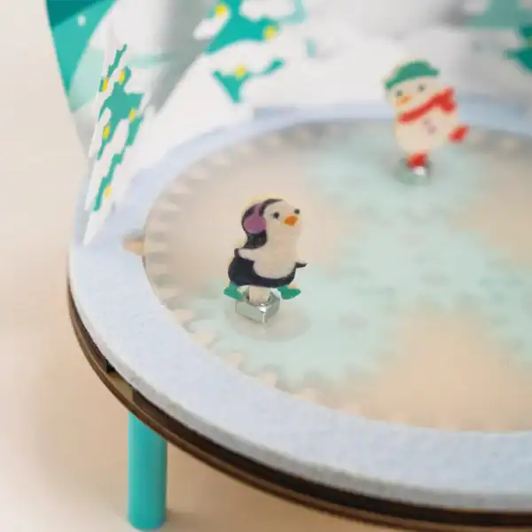 Miniature penguin and snowman figurines in winter scene.
